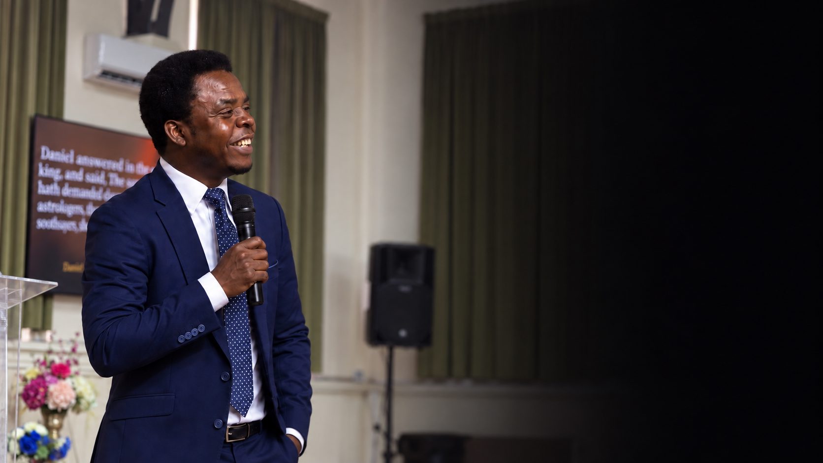 Our pastor smiling on stage with a microphone